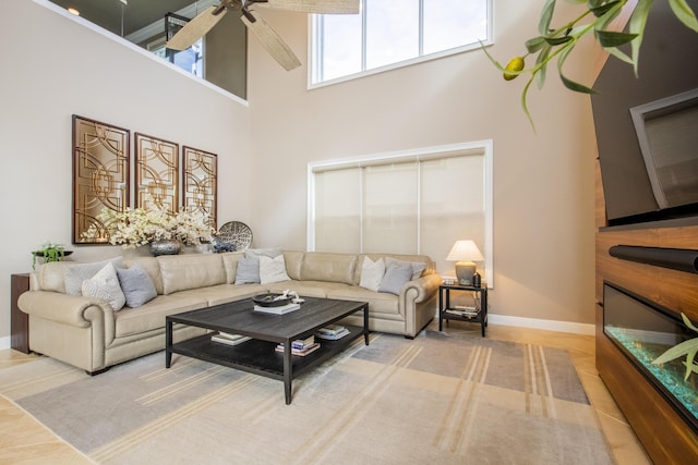 living room with ceiling fan and a towering ceiling