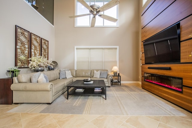 living room featuring a high ceiling, ceiling fan, and tile patterned floors