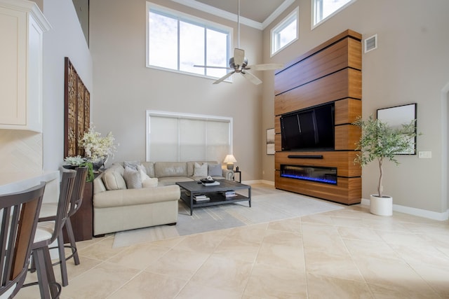 tiled living room featuring ornamental molding, ceiling fan, and a high ceiling