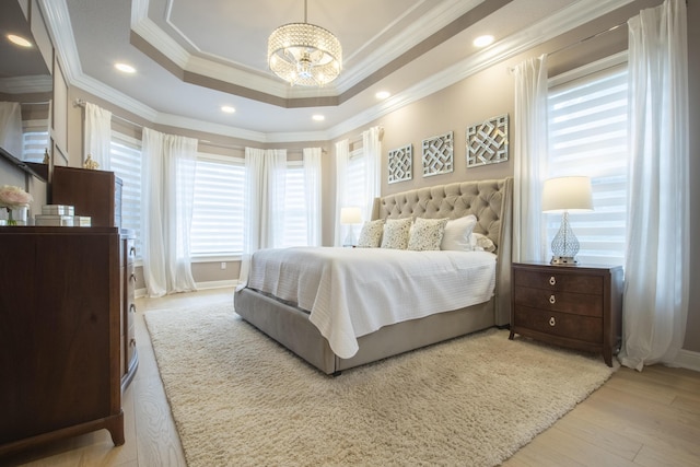 bedroom with a raised ceiling, a chandelier, crown molding, and light hardwood / wood-style flooring