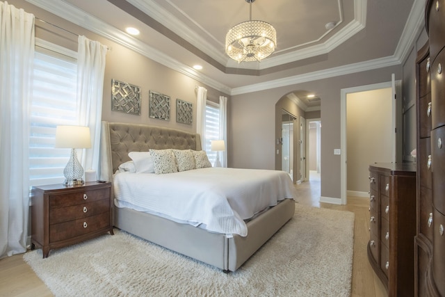 bedroom featuring a raised ceiling, ornamental molding, and a notable chandelier