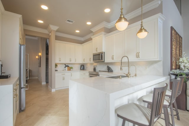 kitchen featuring white cabinets, pendant lighting, kitchen peninsula, and appliances with stainless steel finishes