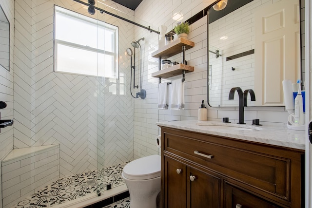 bathroom with toilet, tiled shower, and vanity