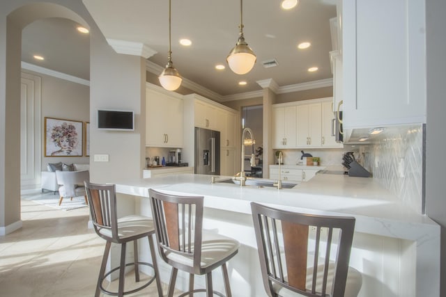 kitchen with decorative light fixtures, white cabinets, kitchen peninsula, decorative backsplash, and high end refrigerator