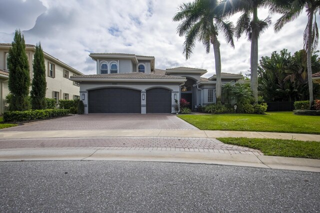 mediterranean / spanish home featuring a front yard and a garage