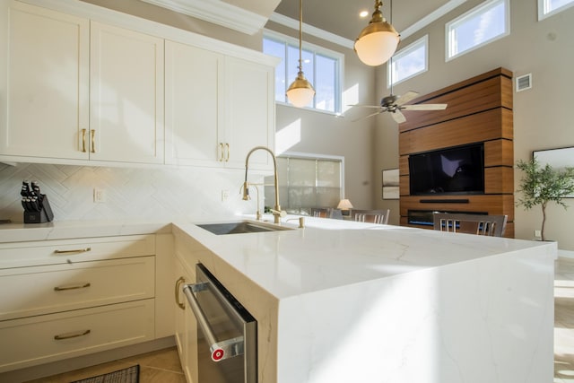 kitchen with dishwasher, light stone countertops, pendant lighting, sink, and backsplash