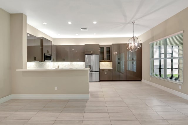 kitchen with kitchen peninsula, appliances with stainless steel finishes, backsplash, light tile patterned floors, and pendant lighting