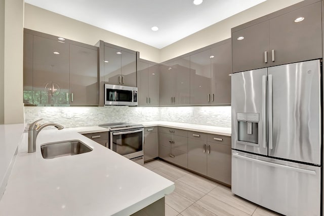 kitchen with appliances with stainless steel finishes, gray cabinets, light tile patterned floors, and sink