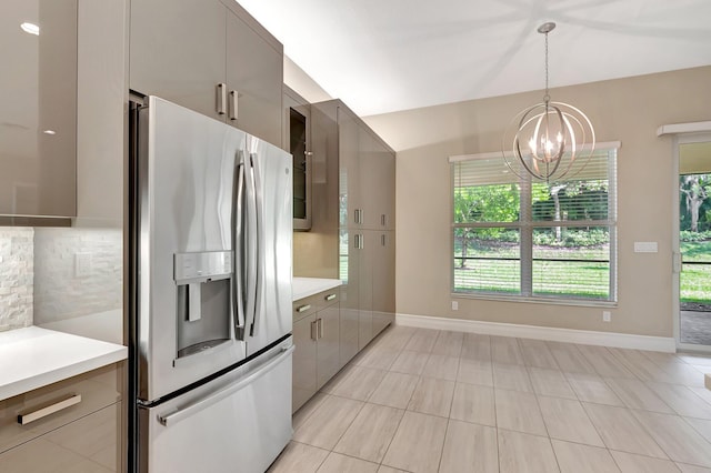 kitchen featuring stainless steel refrigerator with ice dispenser, tasteful backsplash, decorative light fixtures, and a notable chandelier