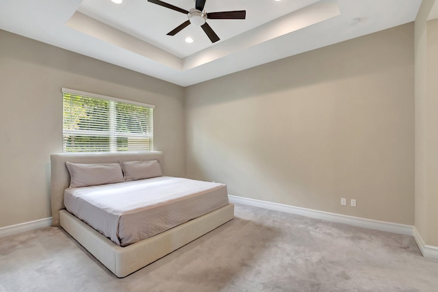 bedroom featuring a tray ceiling, ceiling fan, and light colored carpet