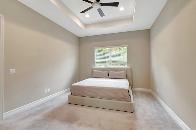 bedroom with ceiling fan, carpet floors, and a tray ceiling