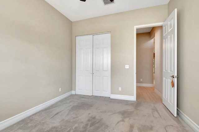 unfurnished bedroom with light carpet, a closet, and ceiling fan