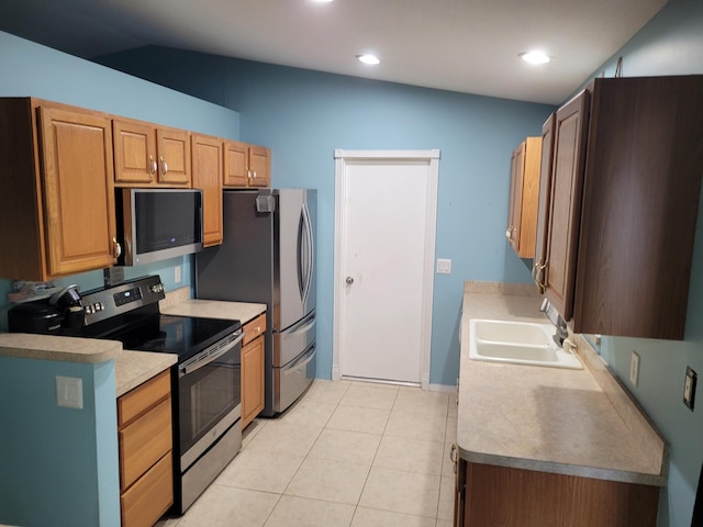 kitchen with sink, stainless steel appliances, vaulted ceiling, and light tile patterned floors