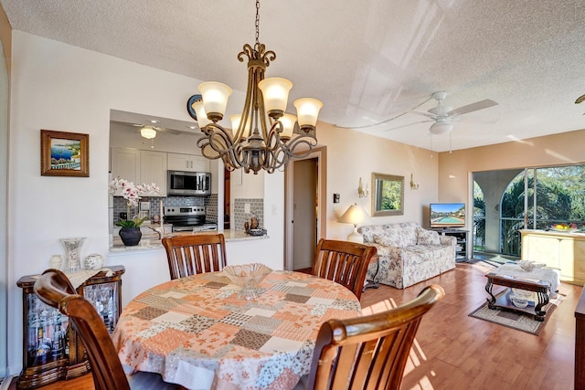 dining room with a textured ceiling, wood finished floors, and ceiling fan with notable chandelier