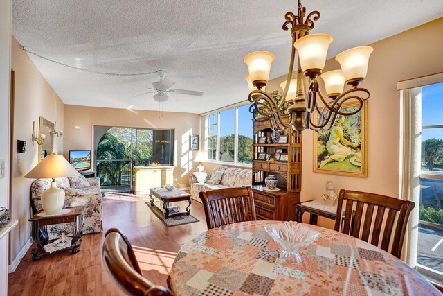 dining space featuring ceiling fan with notable chandelier, a textured ceiling, and hardwood / wood-style flooring