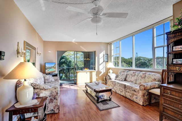 living room with a ceiling fan, a textured ceiling, and wood finished floors