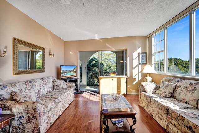 living room featuring ceiling fan with notable chandelier, a textured ceiling, and hardwood / wood-style flooring