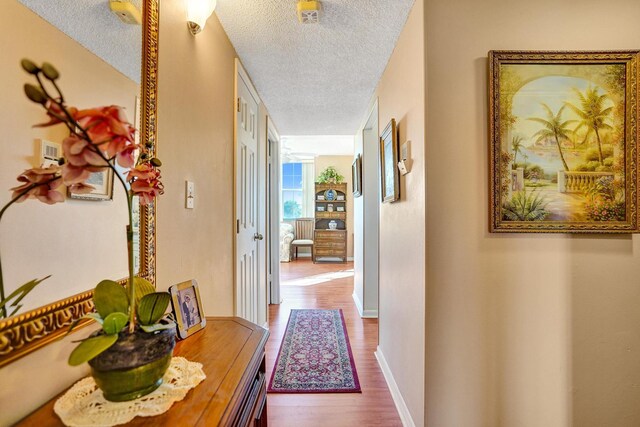 hall featuring a textured ceiling and light hardwood / wood-style flooring