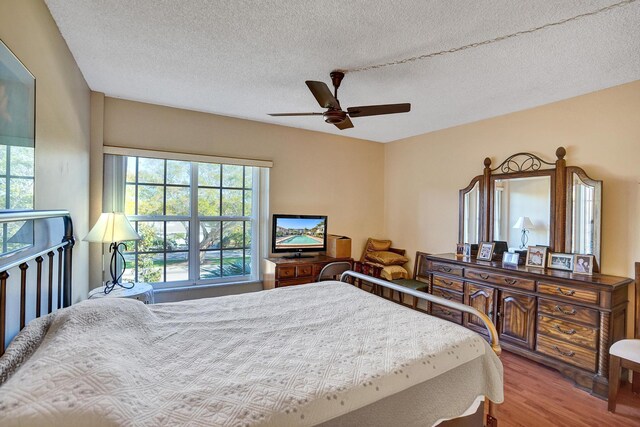 bedroom with ceiling fan, dark hardwood / wood-style flooring, and a textured ceiling