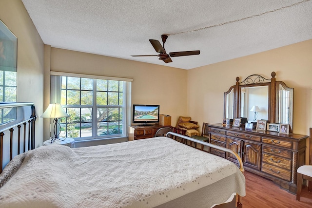 bedroom featuring ceiling fan, a textured ceiling, and wood finished floors