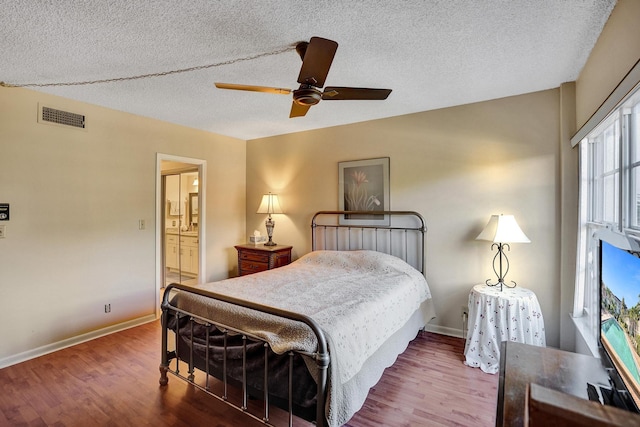 bedroom featuring a textured ceiling, wood finished floors, visible vents, and baseboards