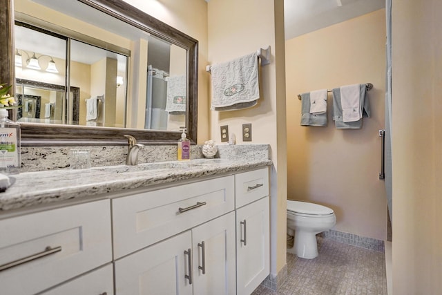 bathroom featuring toilet, tile patterned floors, baseboards, and vanity