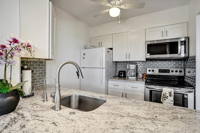 kitchen featuring decorative backsplash, appliances with stainless steel finishes, light stone countertops, white cabinetry, and a sink