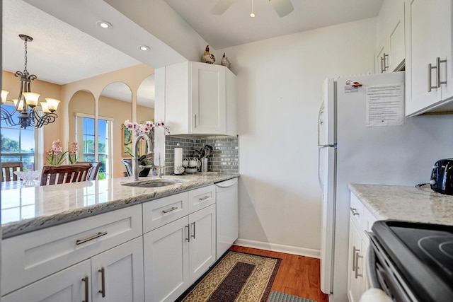 kitchen featuring white dishwasher, tasteful backsplash, wood finished floors, a sink, and white cabinets
