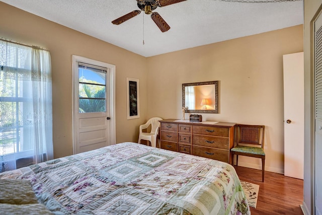 bedroom with a textured ceiling, wood finished floors, and a ceiling fan