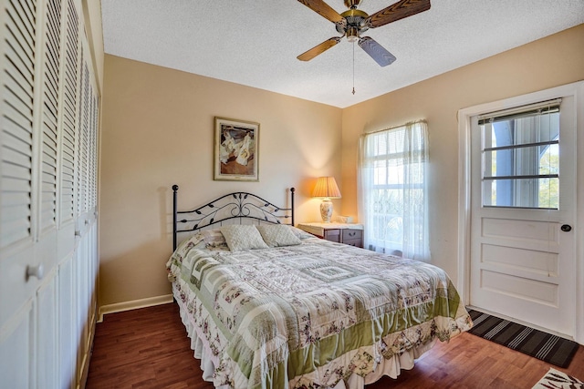 bedroom with ceiling fan, a textured ceiling, baseboards, a closet, and dark wood-type flooring