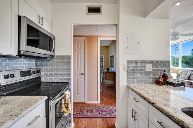 kitchen with light stone countertops, white cabinetry, and appliances with stainless steel finishes