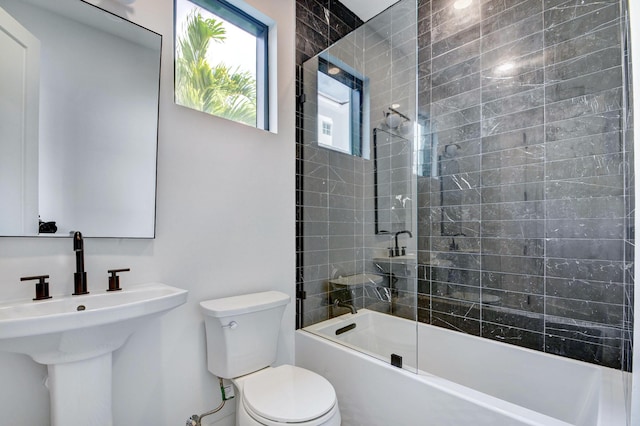 full bathroom with sink, bath / shower combo with glass door, and toilet