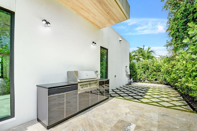 view of patio with exterior kitchen and a grill