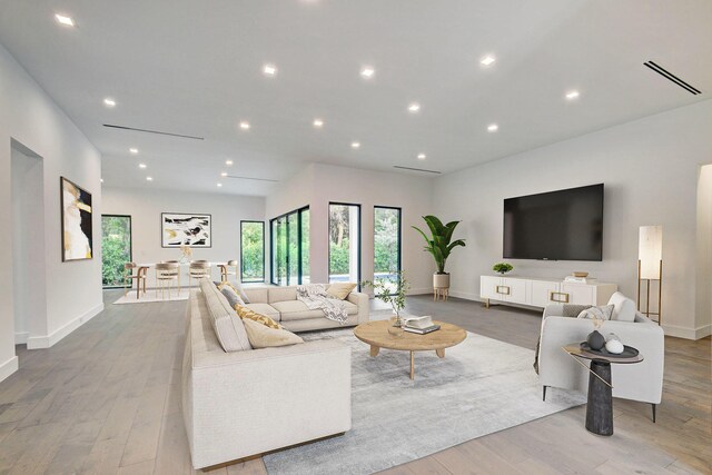 kitchen with appliances with stainless steel finishes, white cabinetry, wall chimney exhaust hood, and a spacious island