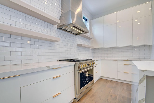 kitchen with white cabinets, ventilation hood, light stone counters, and high end range