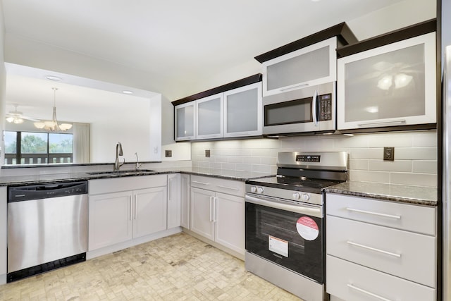 kitchen with white cabinetry, sink, dark stone countertops, hanging light fixtures, and stainless steel appliances