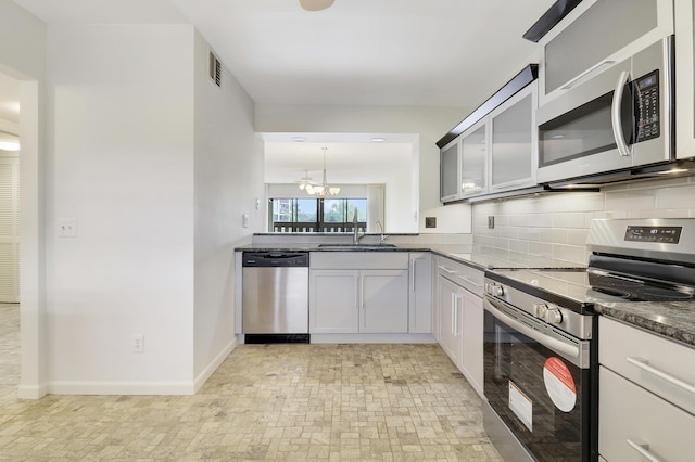 kitchen featuring pendant lighting, sink, backsplash, stainless steel appliances, and a chandelier