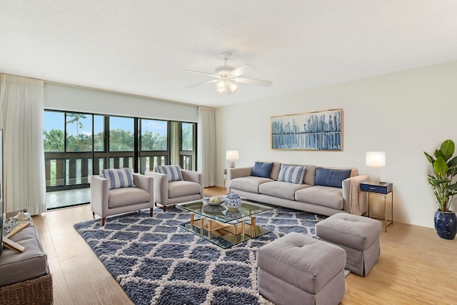 living room featuring ceiling fan, light hardwood / wood-style floors, and a textured ceiling