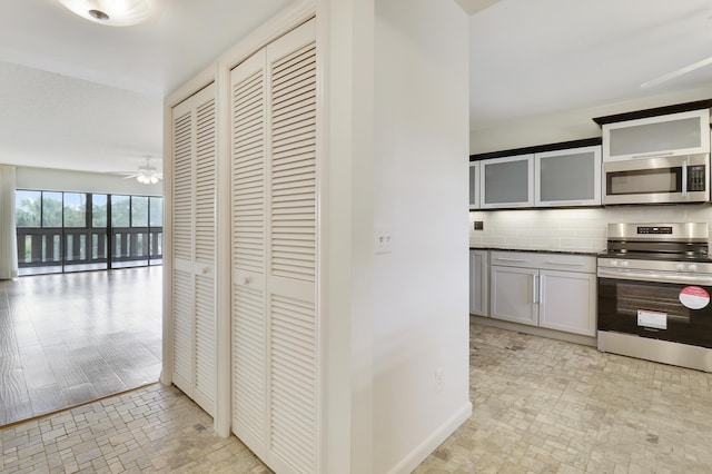 kitchen with tasteful backsplash, white cabinetry, appliances with stainless steel finishes, and ceiling fan