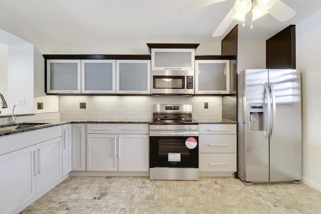 kitchen with sink, white cabinets, dark stone counters, decorative backsplash, and stainless steel appliances