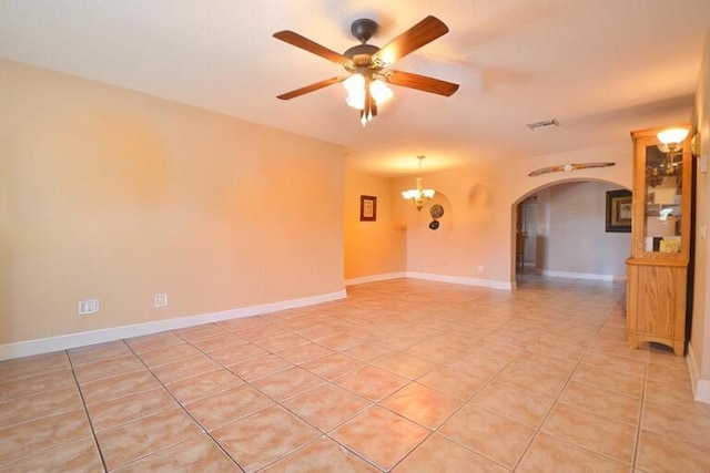 tiled spare room with ceiling fan with notable chandelier