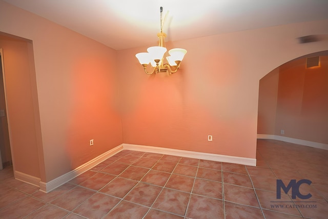 tiled empty room featuring an inviting chandelier