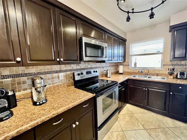 kitchen with sink, light tile patterned flooring, tasteful backsplash, dark brown cabinetry, and appliances with stainless steel finishes