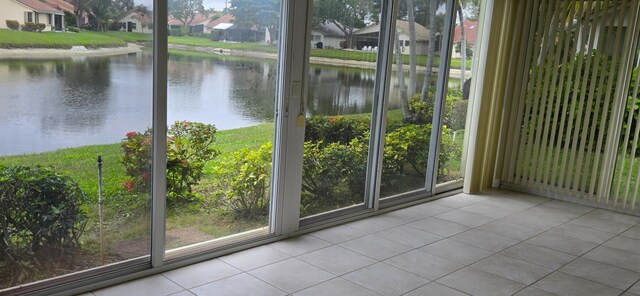 doorway to outside featuring a water view and light tile patterned floors