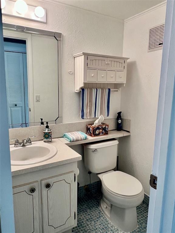 bathroom featuring tile patterned flooring, vanity, toilet, and crown molding