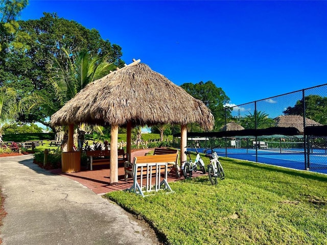 view of property's community with a gazebo, tennis court, and a lawn