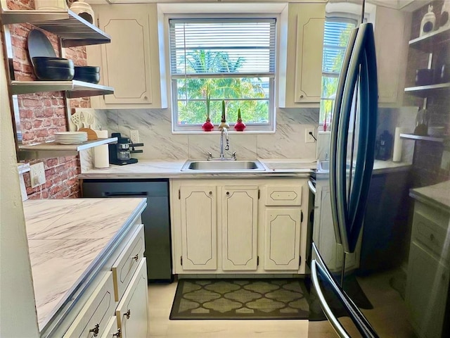 kitchen featuring black refrigerator, backsplash, plenty of natural light, and sink