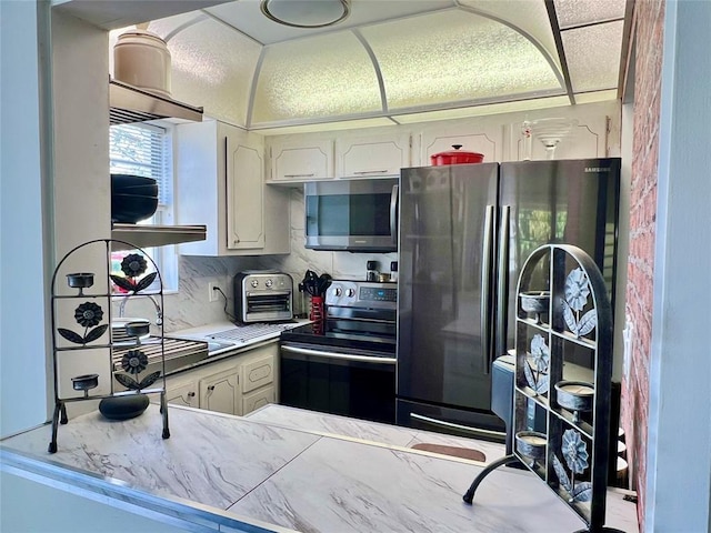 kitchen with backsplash, kitchen peninsula, white cabinetry, and stainless steel appliances