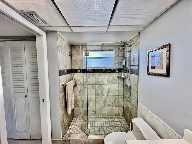 bathroom featuring tile patterned floors, toilet, and a shower with door