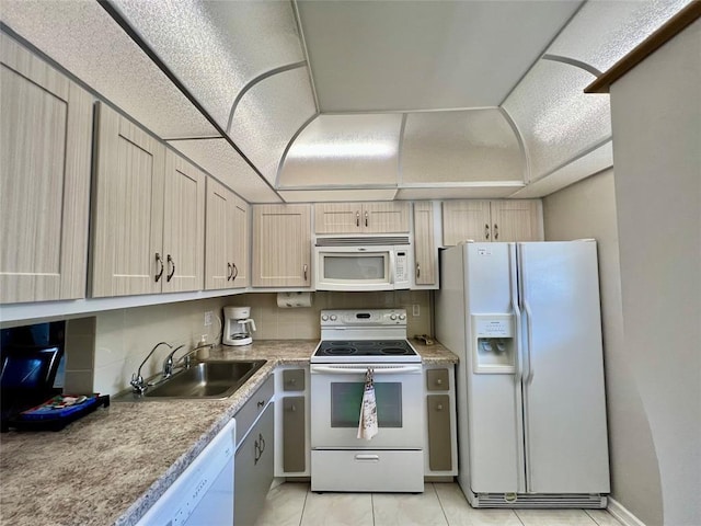 kitchen with light tile patterned floors, white appliances, light brown cabinets, and sink